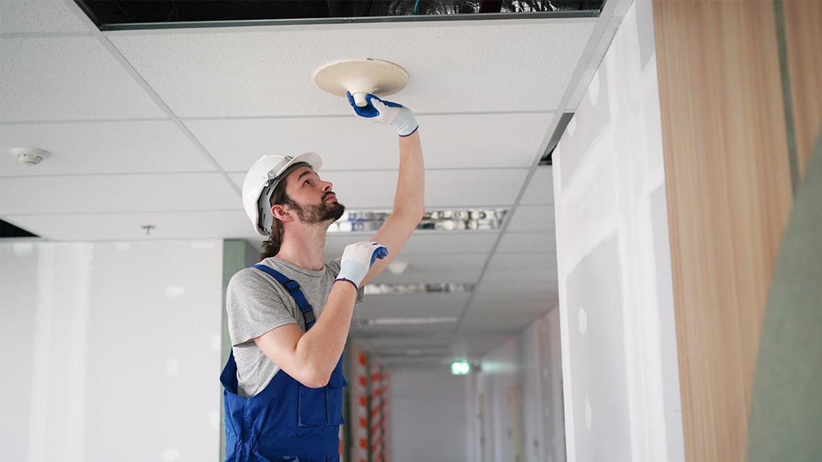 workman installing LED lighting in an office